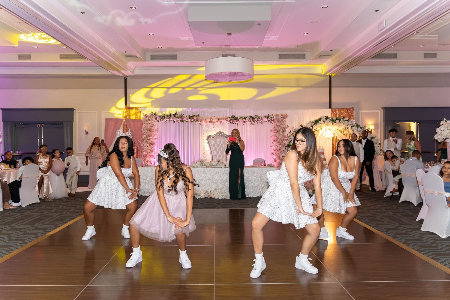 Young girls in white dresses perform a choreographed dance at an elegant ballroom celebration event. Sweet 16!