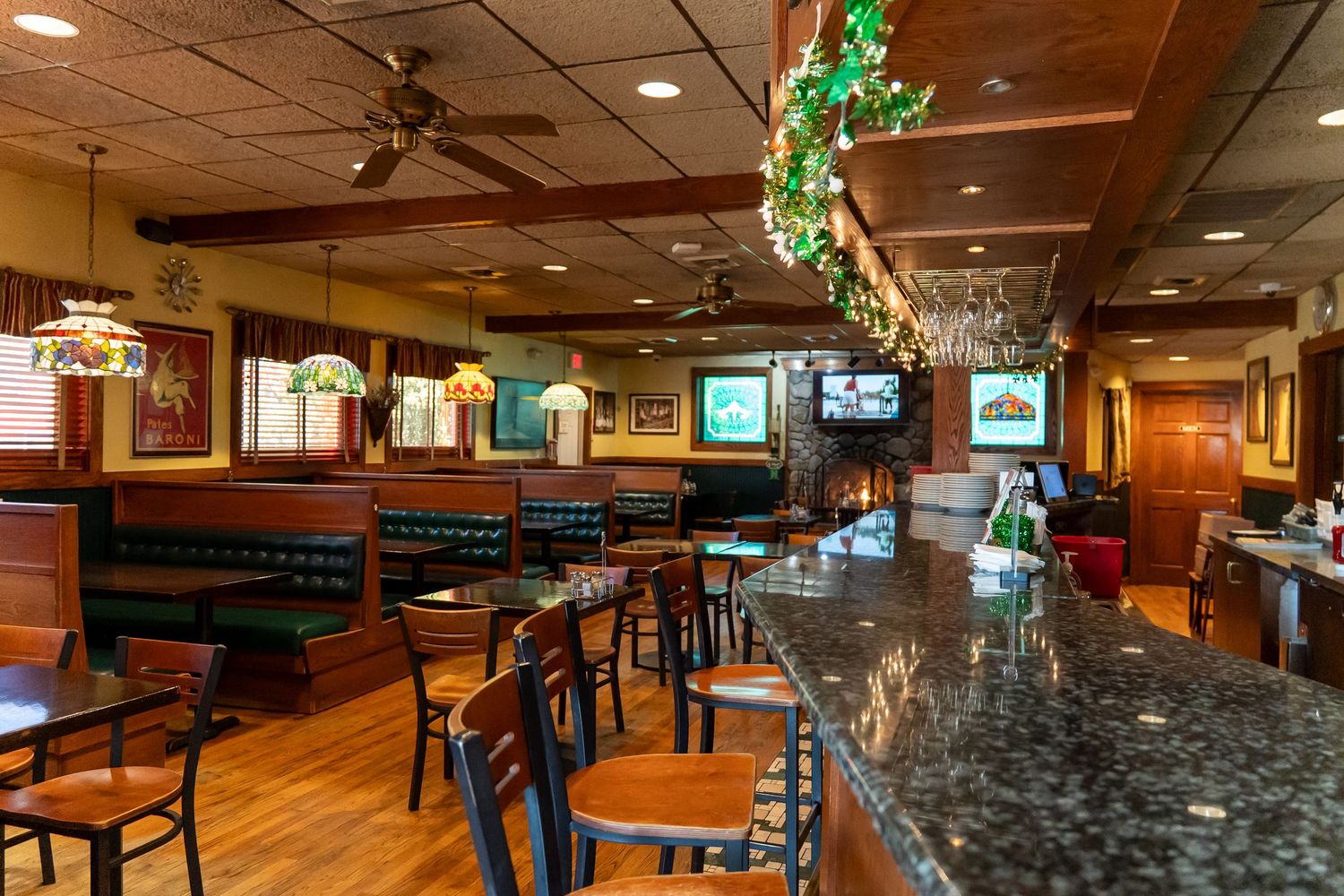 Warm interior of casual restaurant bar with wood paneling, granite counter and pendant lights.