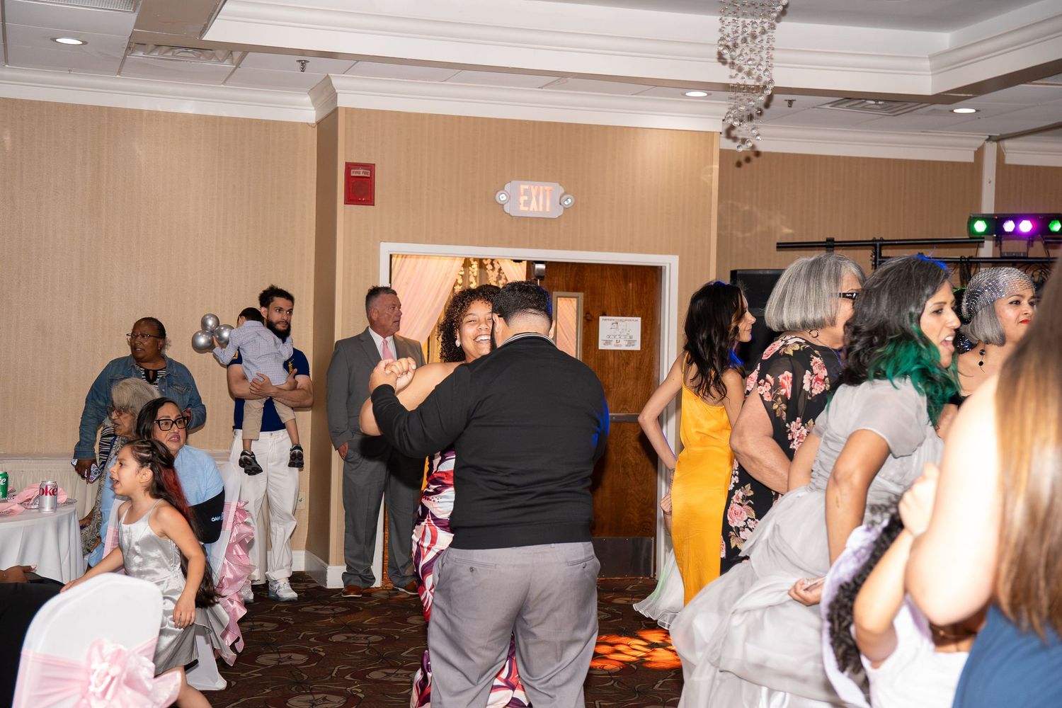 Guests dancing and socializing at an elegant indoor wedding reception in a decorated banquet hall. Sweet 16!