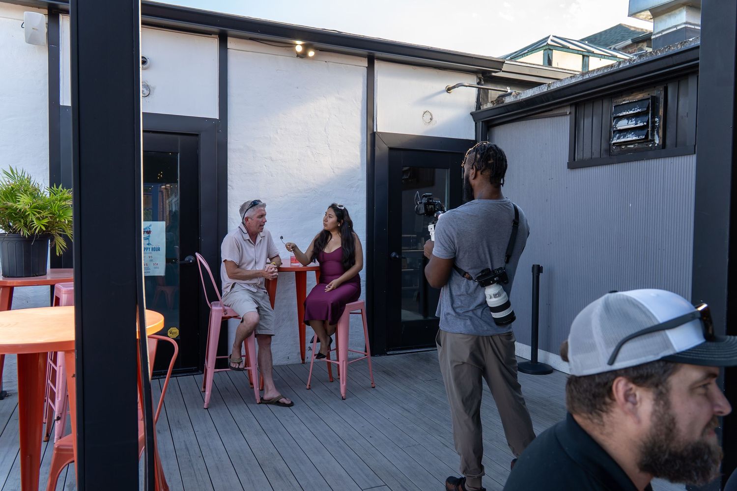 People socializing on an outdoor patio deck while a photographer captures the moment at dusk.