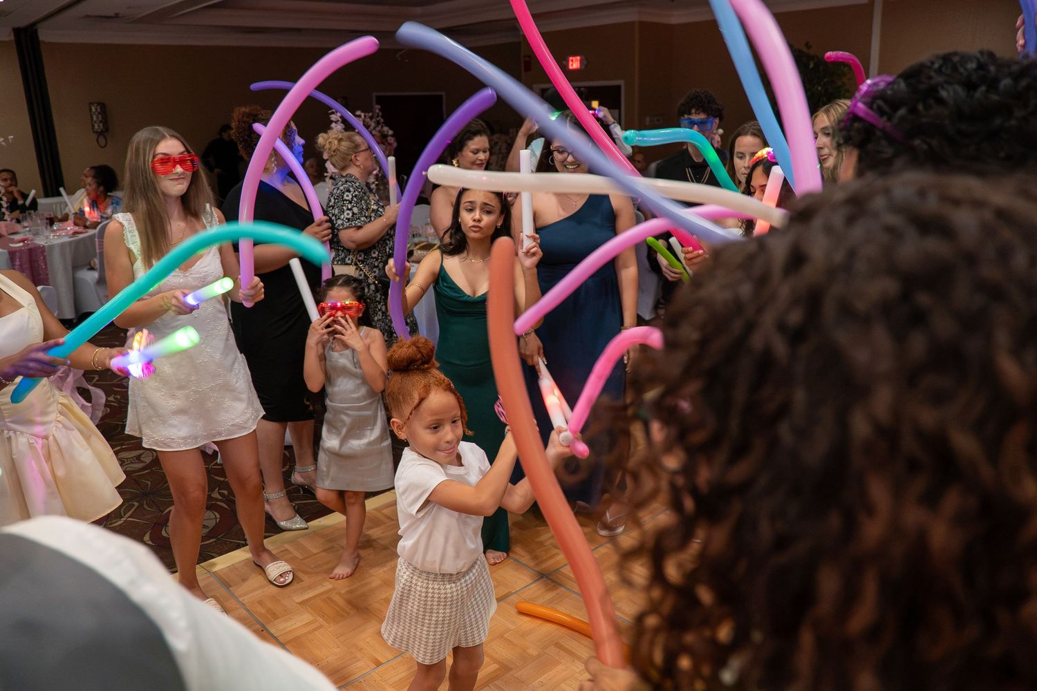 Children and guests dancing with colorful balloon arches at a festive wedding reception celebration. Sweet 16!