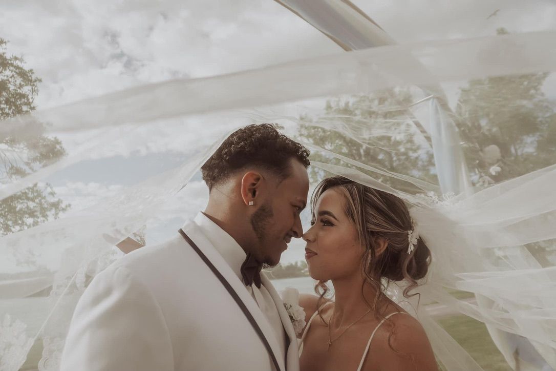 Bride and groom sharing an intimate moment under a flowing veil on their wedding day.