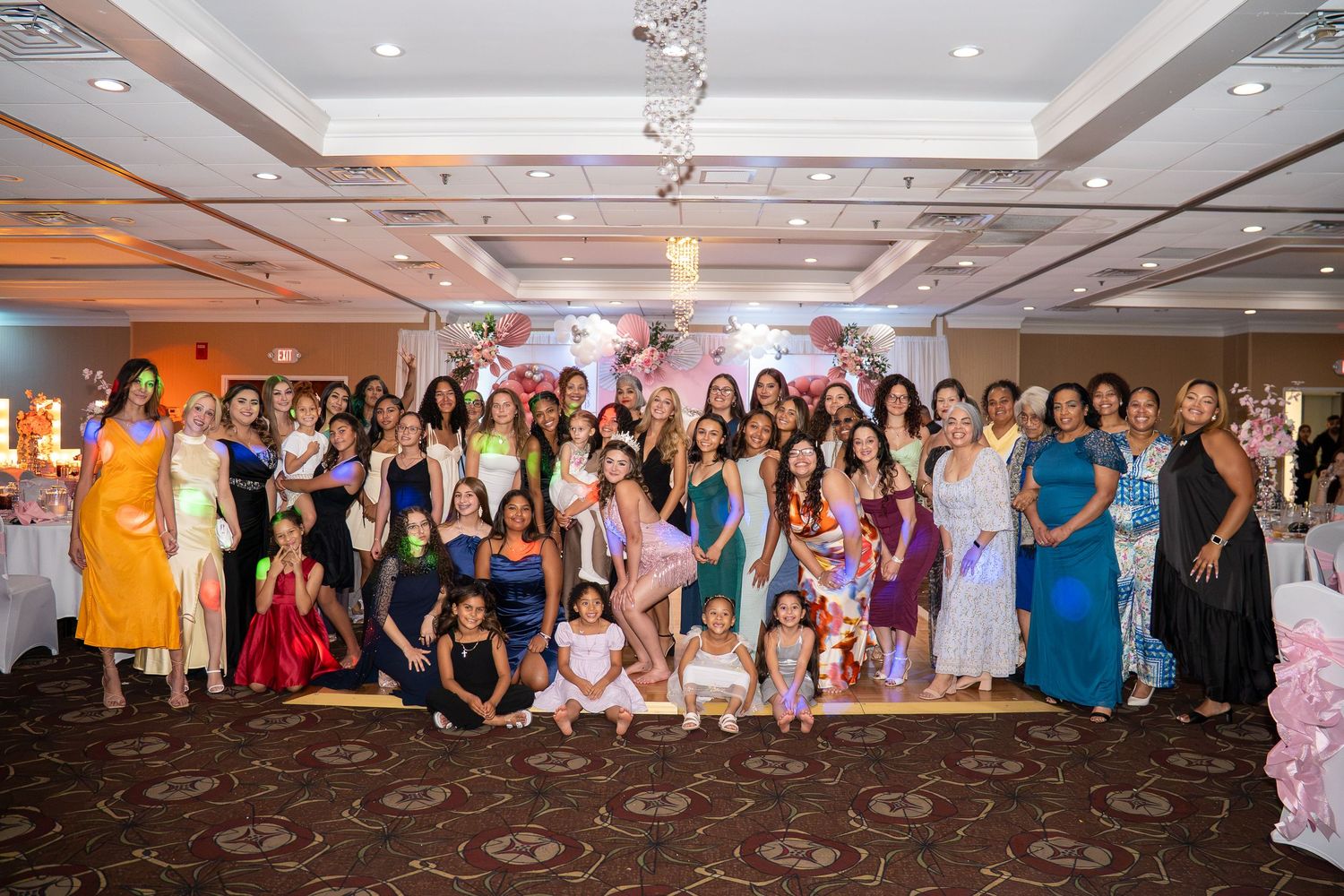 Large group of elegantly dressed women posing together at a formal banquet hall celebration event. Sweet 16!