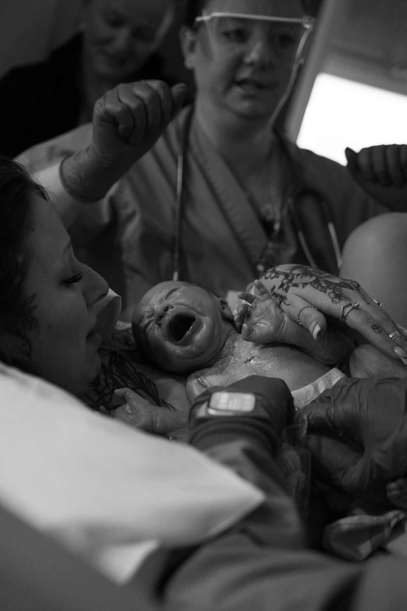 Emotional black and white photo of newborn baby being held by mother in hospital delivery room.