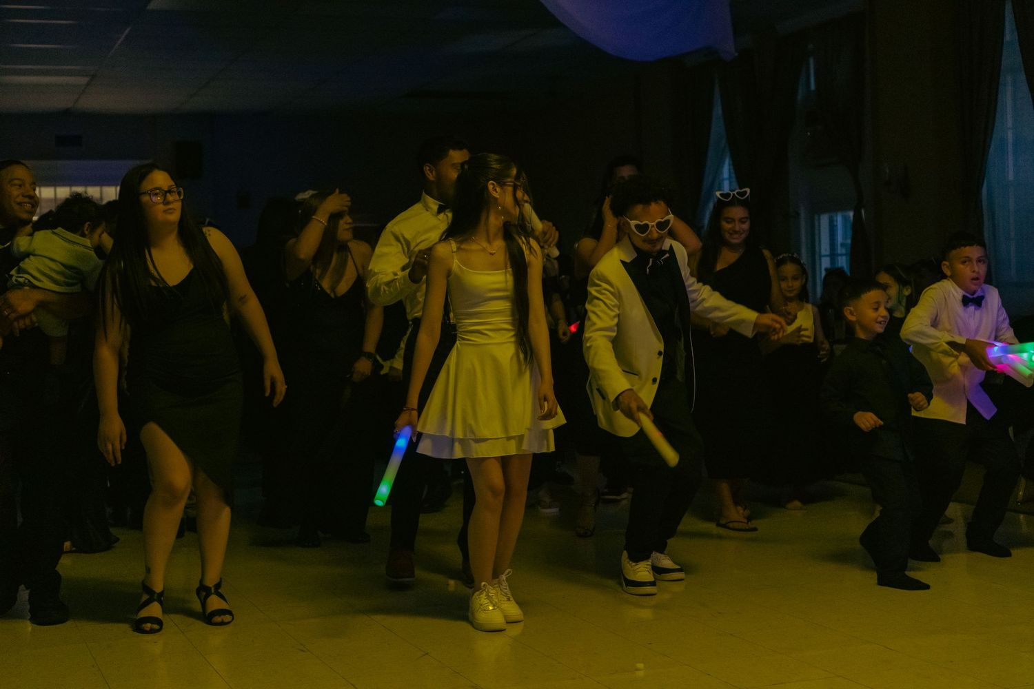 Group of people dancing with glow sticks at an indoor party celebration event.