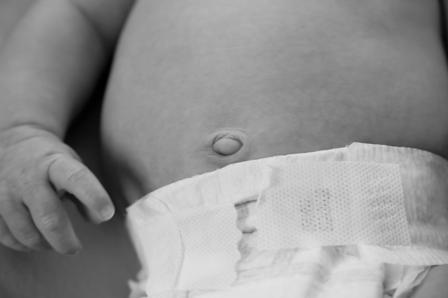 Close-up black and white photo of a newborn baby belly button and diaper. Newborn photoshoot.