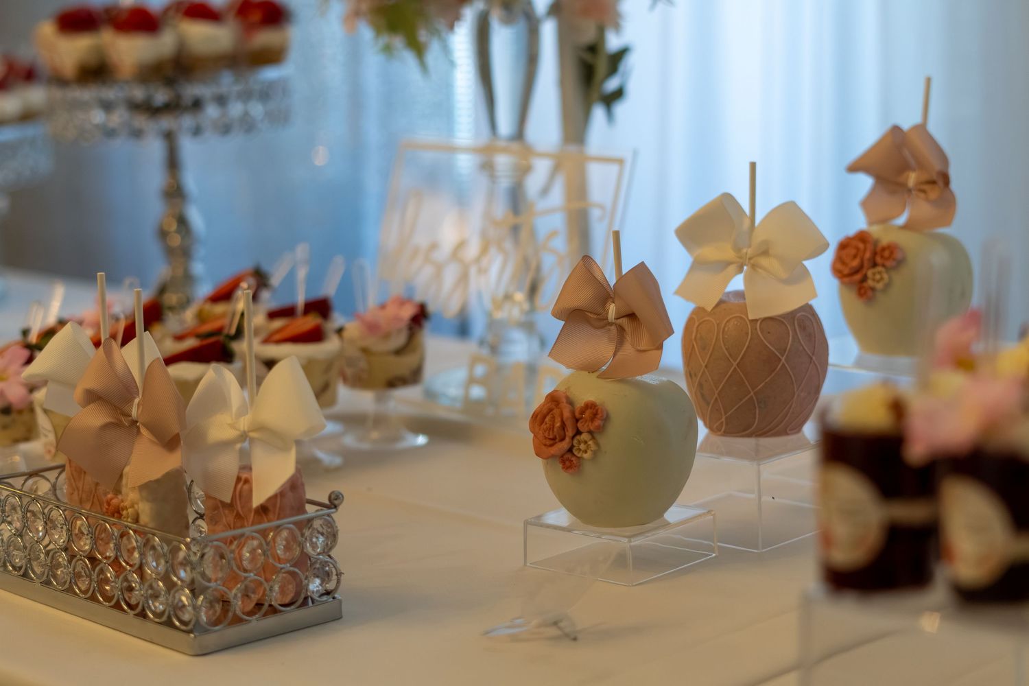 Decorative candy apples and desserts displayed on a white table at an elegant wedding reception. Sweet 16/Quinceañera