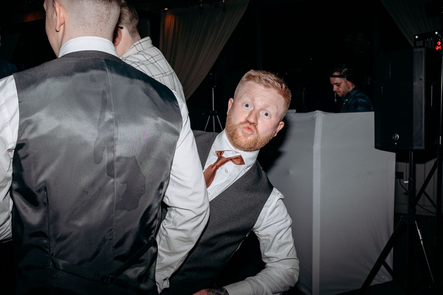 Man in gray vest and bow tie looking back at camera at a formal event.