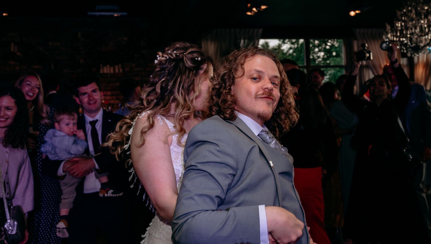 Bride and groom share a dance at their wedding reception in a warmly lit venue.