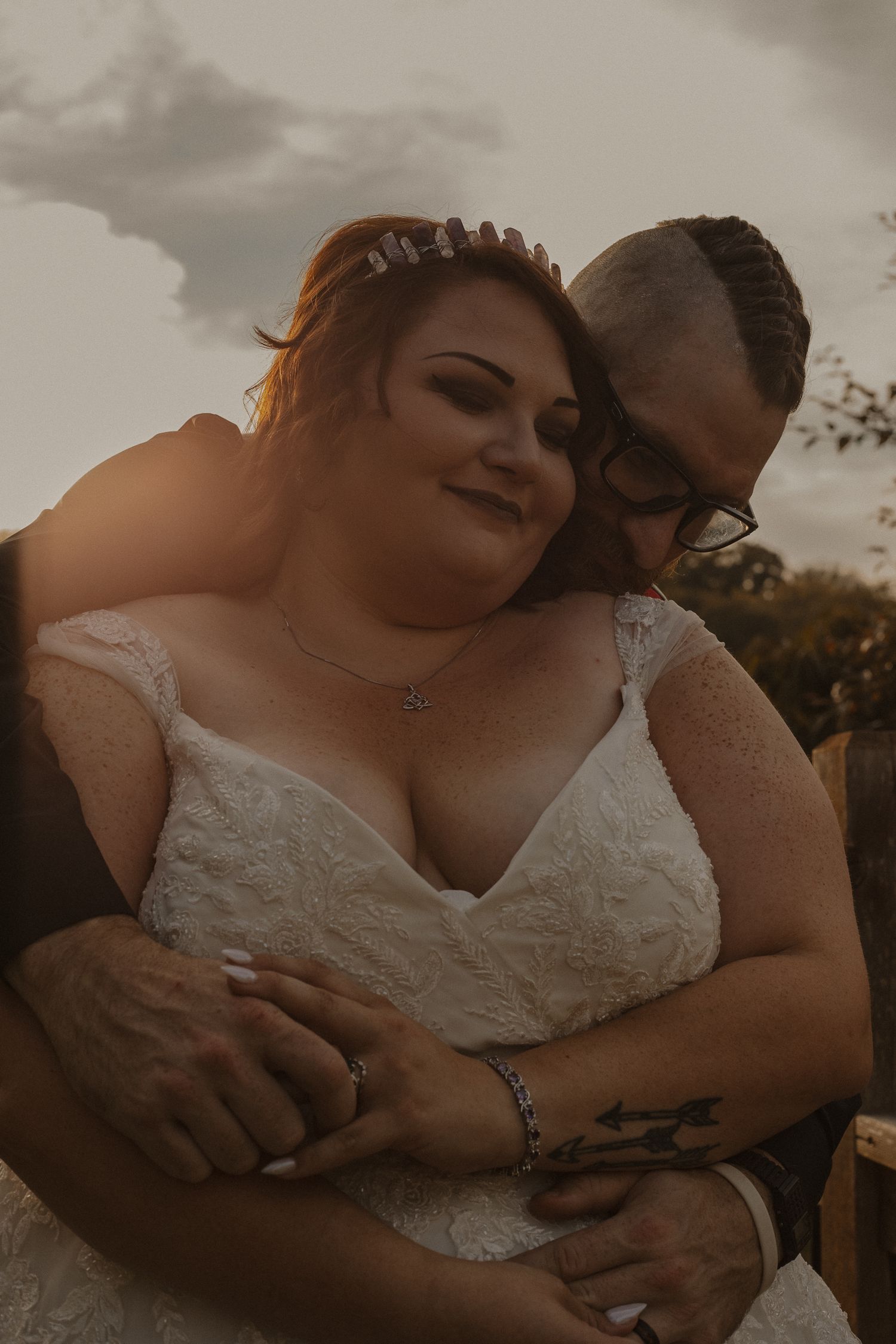 A romantic couple embraces during a sunset photoshoot in their wedding attire.