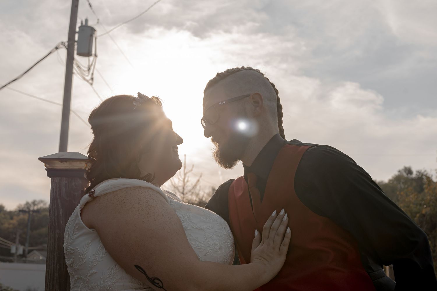 Silhouetted couple embracing during golden hour with sunlight creating a romantic backlit effect.