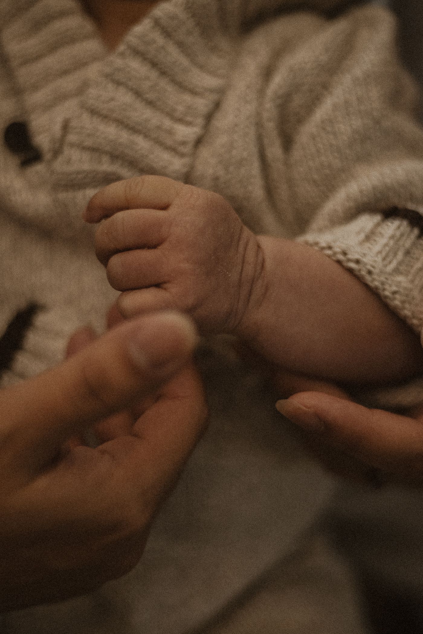 Close-up of hands gently holding and examining a knitted sweater texture in warm lighting.
