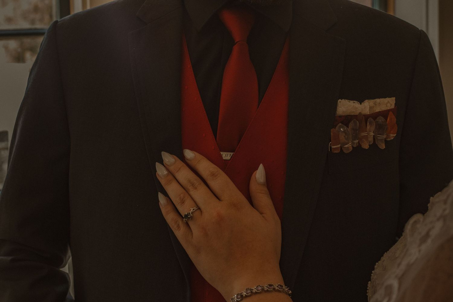 A hand holds up a bright red heart-shaped object against a dark background.