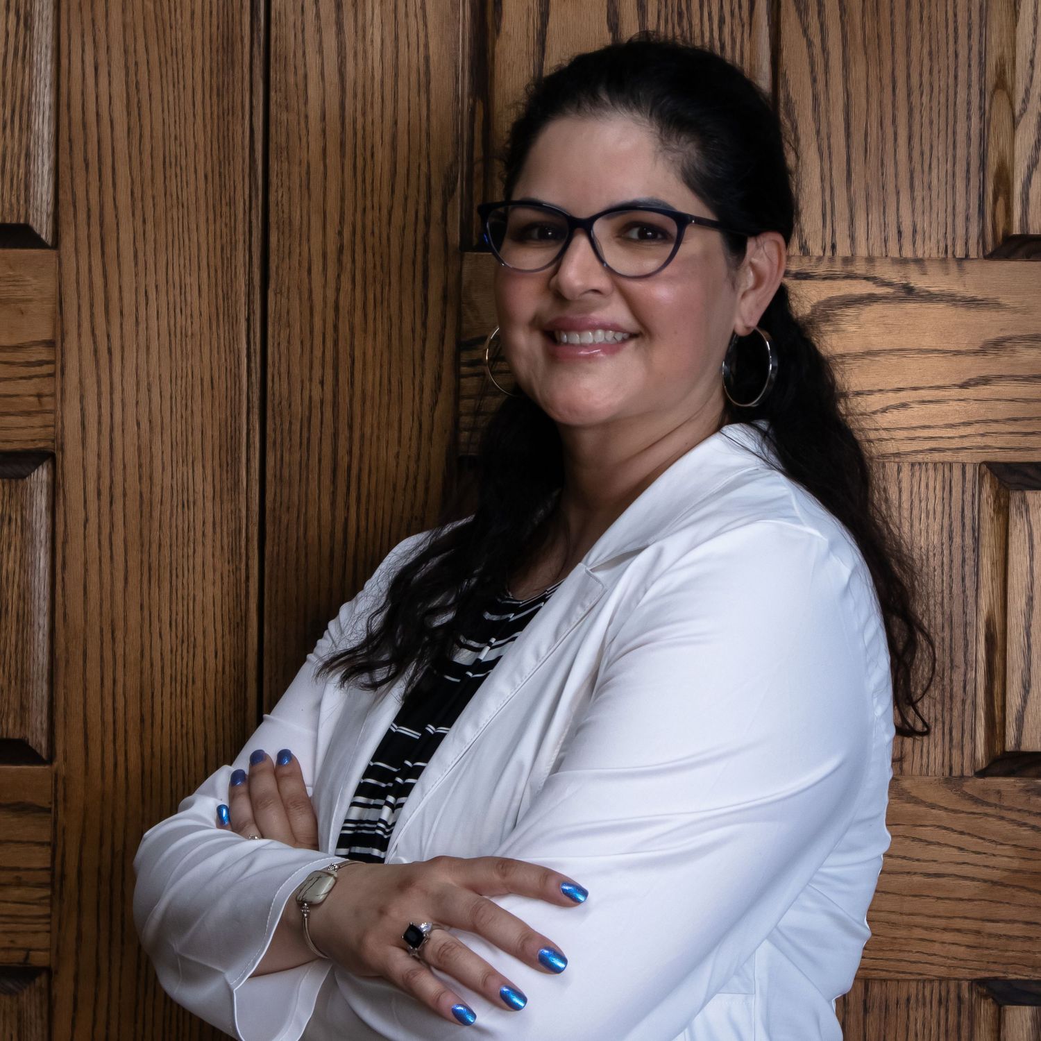 Business portrait showing confident pose in white blazer against textured wood wall.