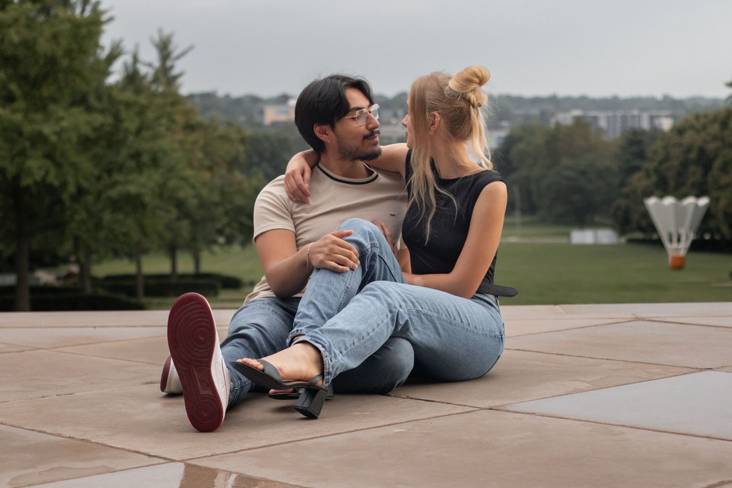 Couple lounging casually on outdoor concrete steps during a sunny day.