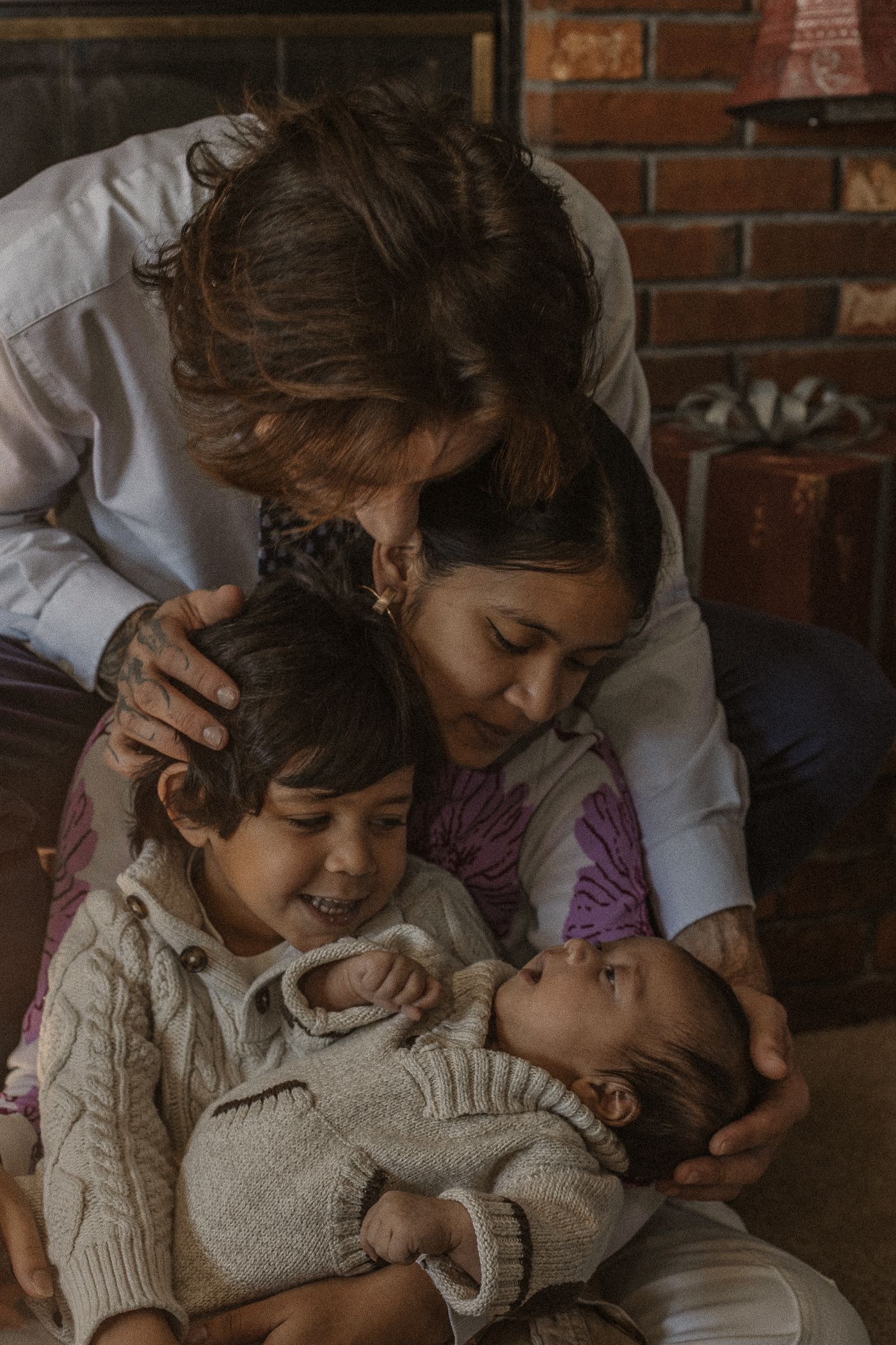 A family shares an intimate moment together on a couch against exposed brick walls in warm lighting.