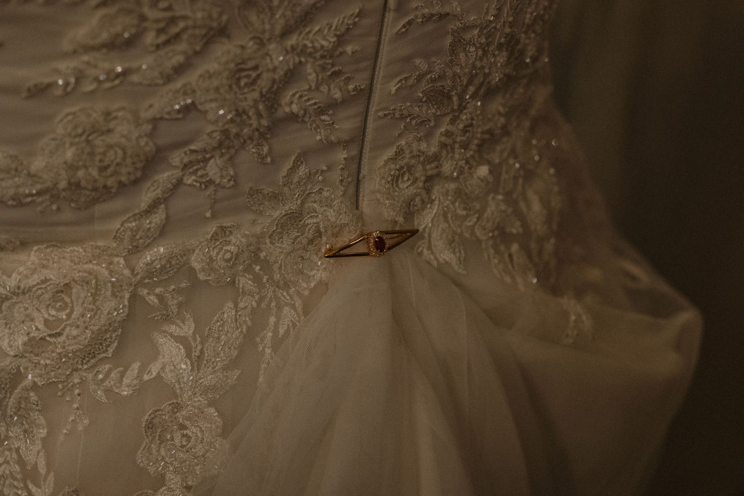 A close-up view of a delicate white lace wedding dress with intricate floral patterns and beading details.