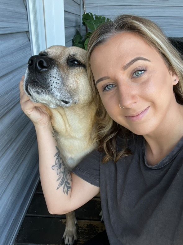 A sweet selfie moment shows a person with blonde hair cuddling next to their happy yellow Labrador dog.