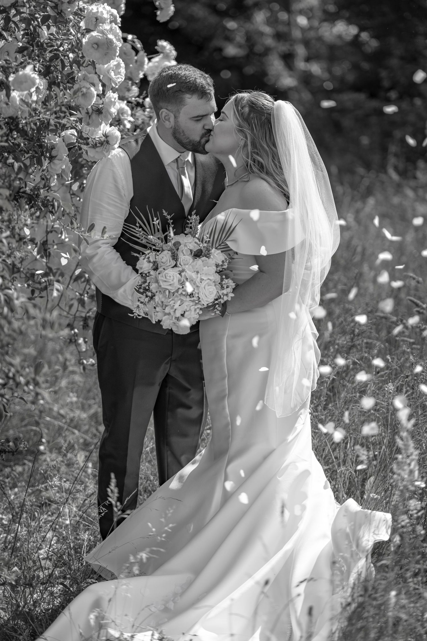 A romantic black and white wedding photo series showing tender moments between newlyweds in an outdoor garden setting.