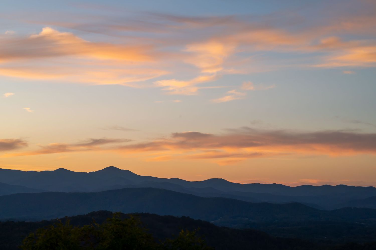 Dramatic sunset panorama over mountain range with deep orange sky.