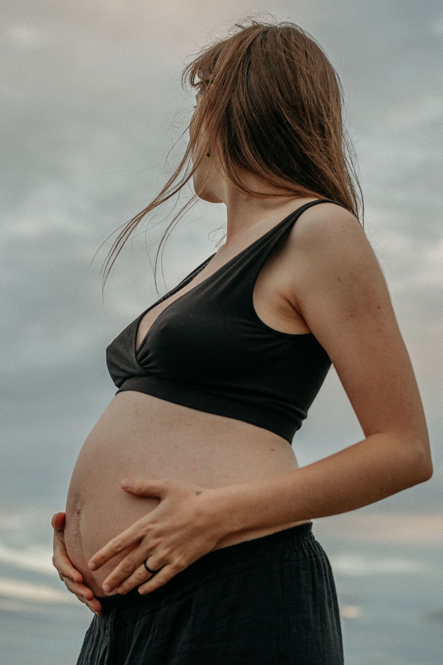 A woman looking into the distance holding her pregnant belly