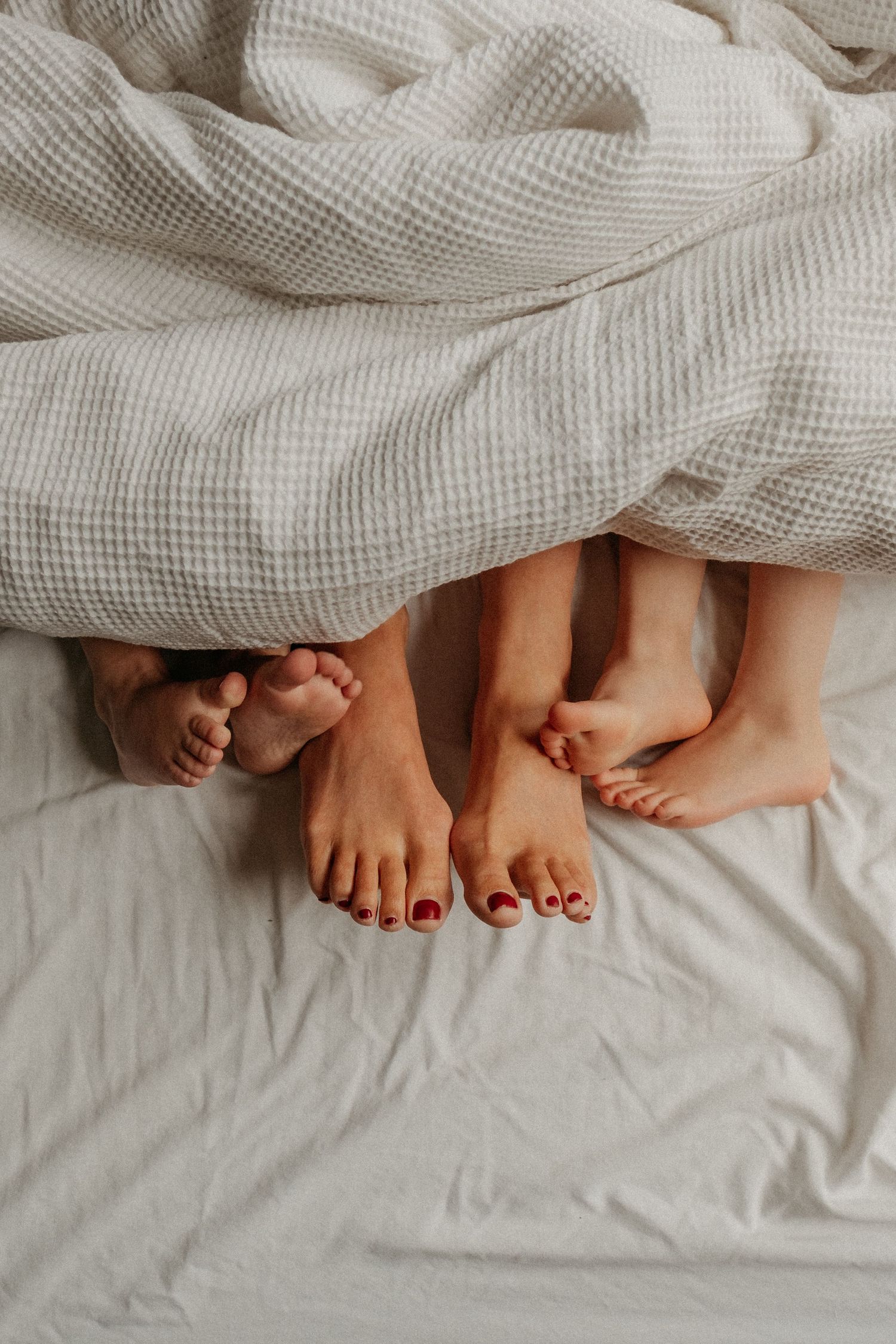 Family feet under a duvet at family portrait session in Heaton