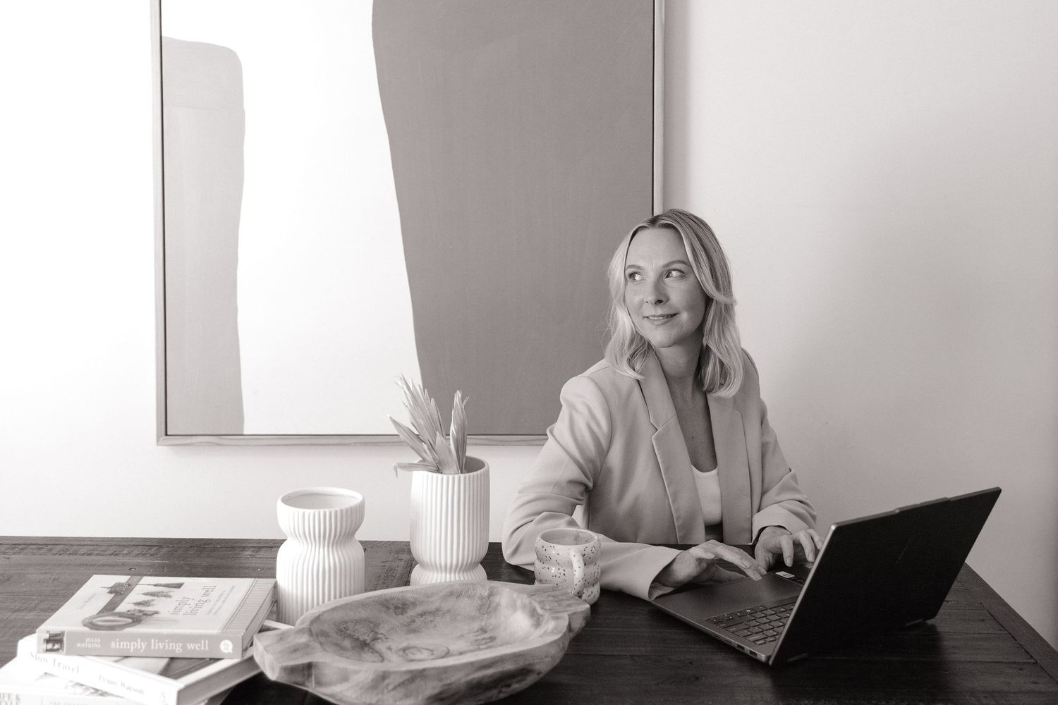 Woman working on laptop at desk in black and white professional photo.