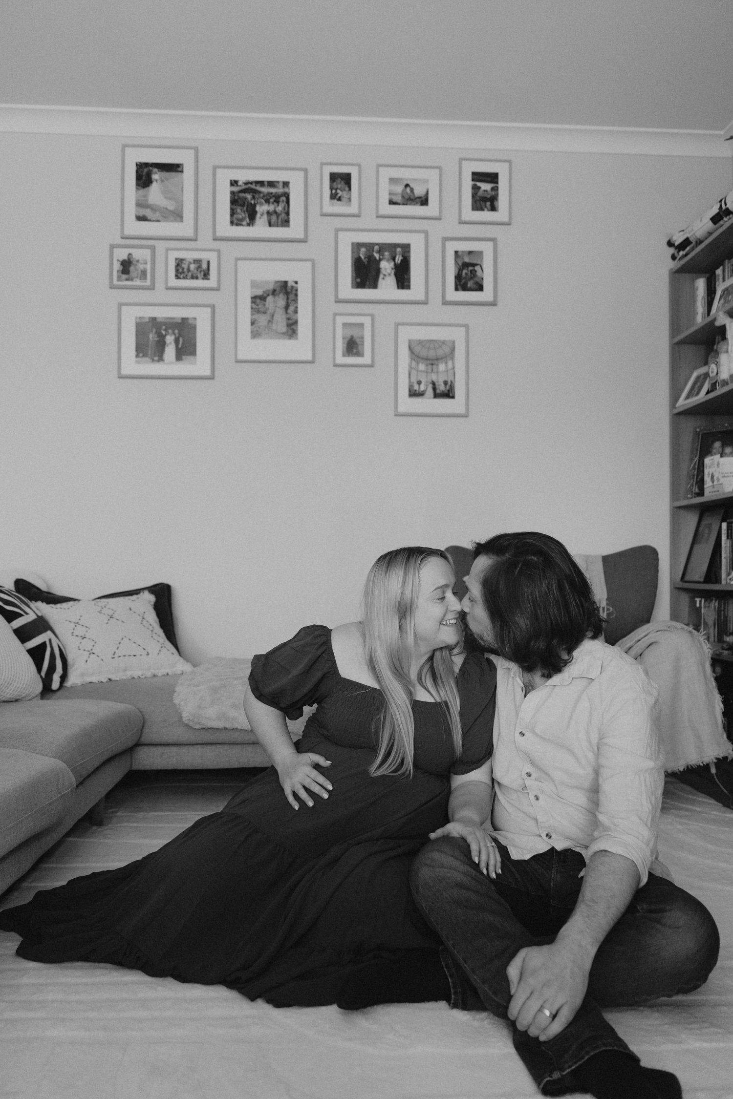 Couple sharing a kiss while sitting on floor in cozy living room.