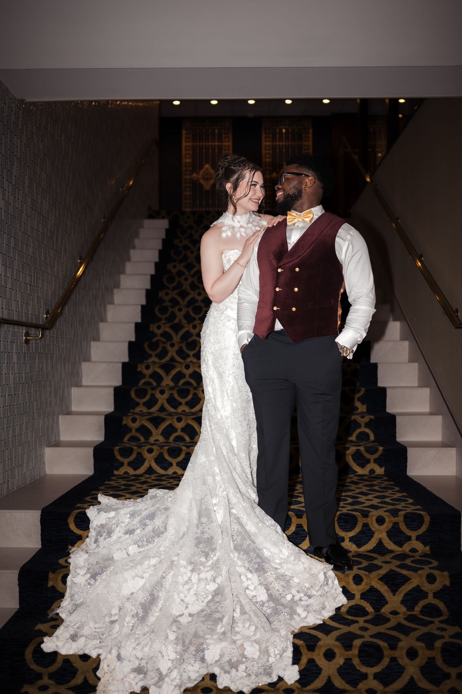 Couple sharing a romantic moment on an elegant staircase with ornate patterned carpet.