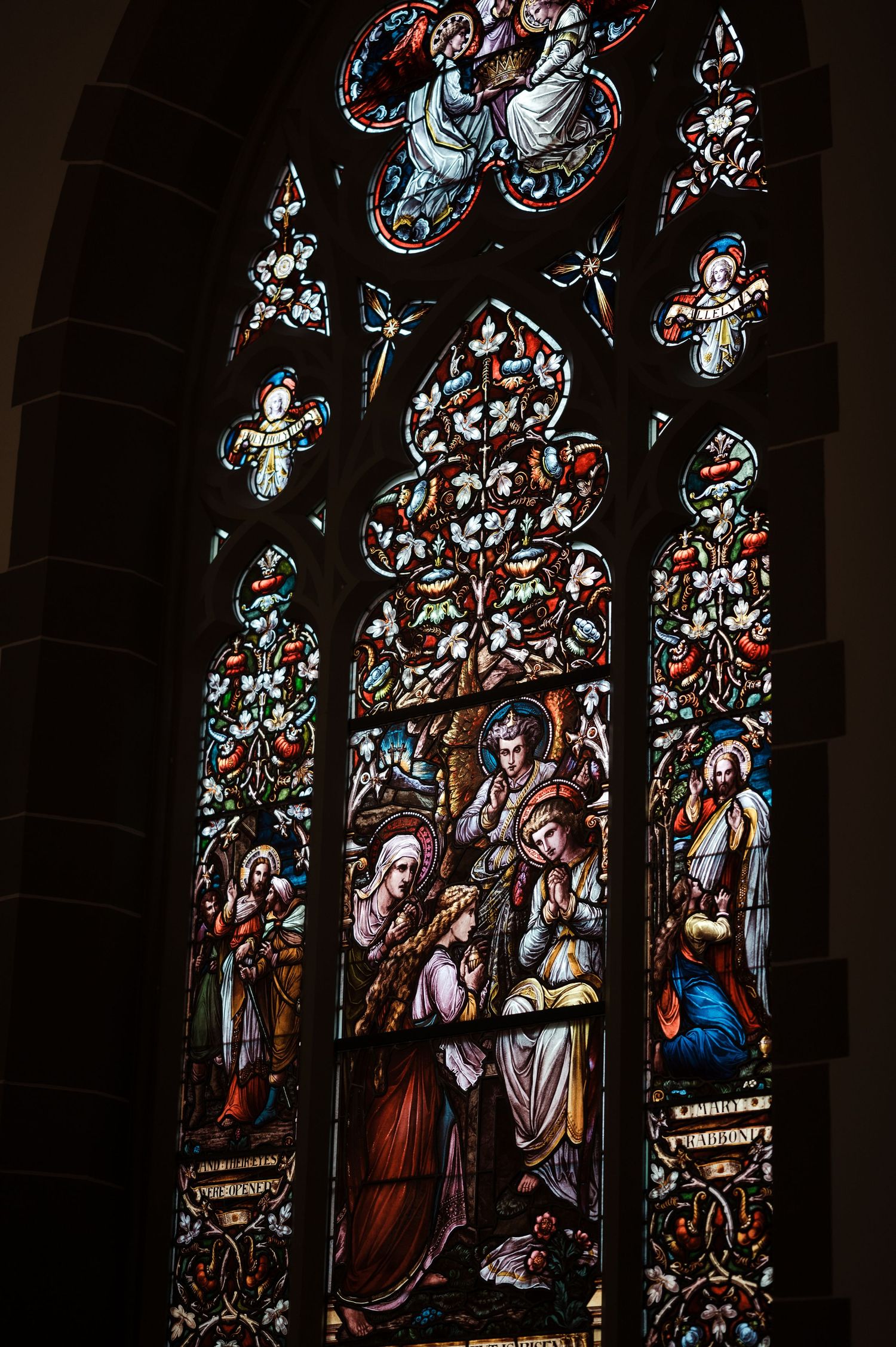 Stained glass church window panels depicting religious figures and scenes in dark tones with blue and red accents.