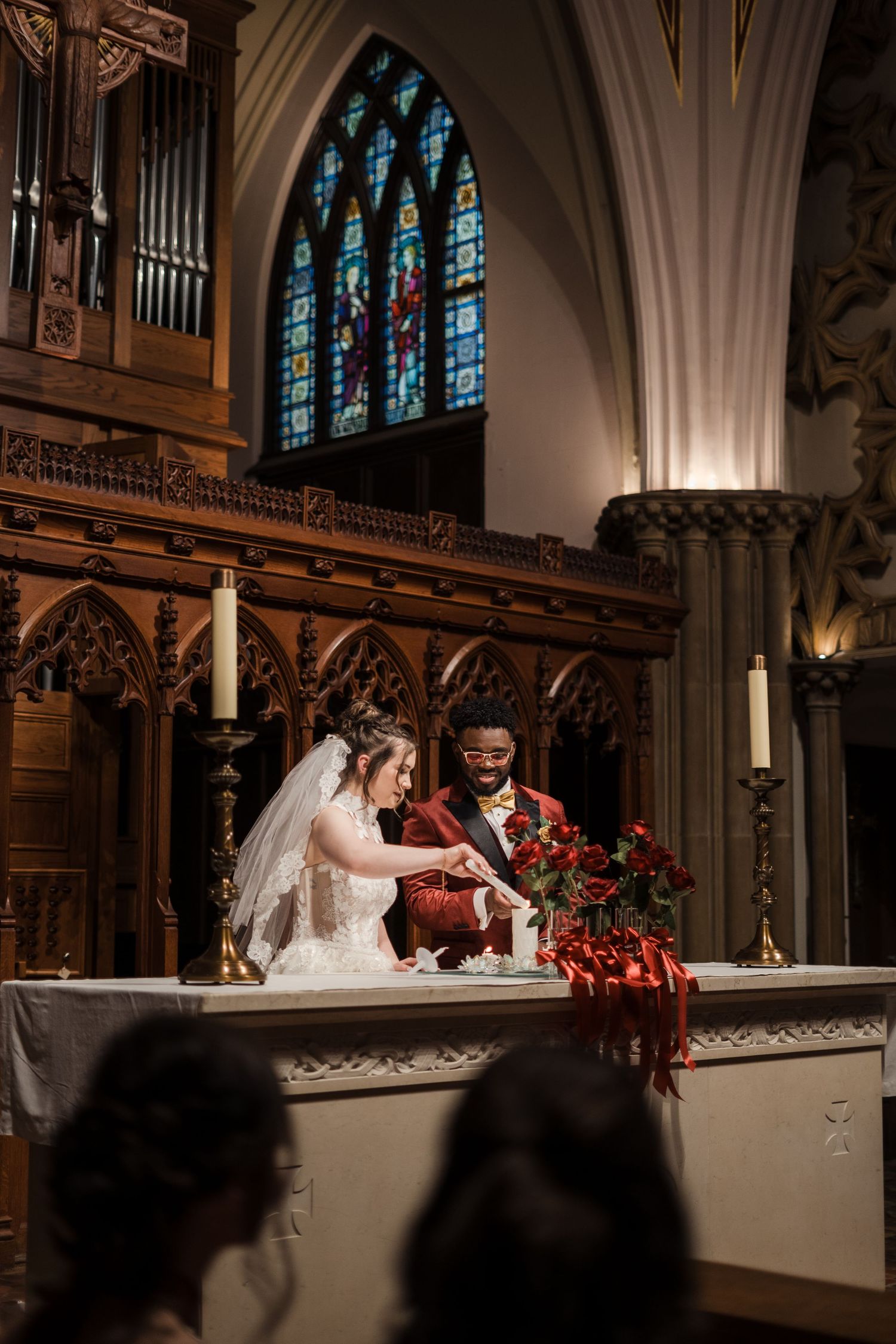 A couple signs documents at an ornate church altar with stained glass windows and gothic architecture in the background.