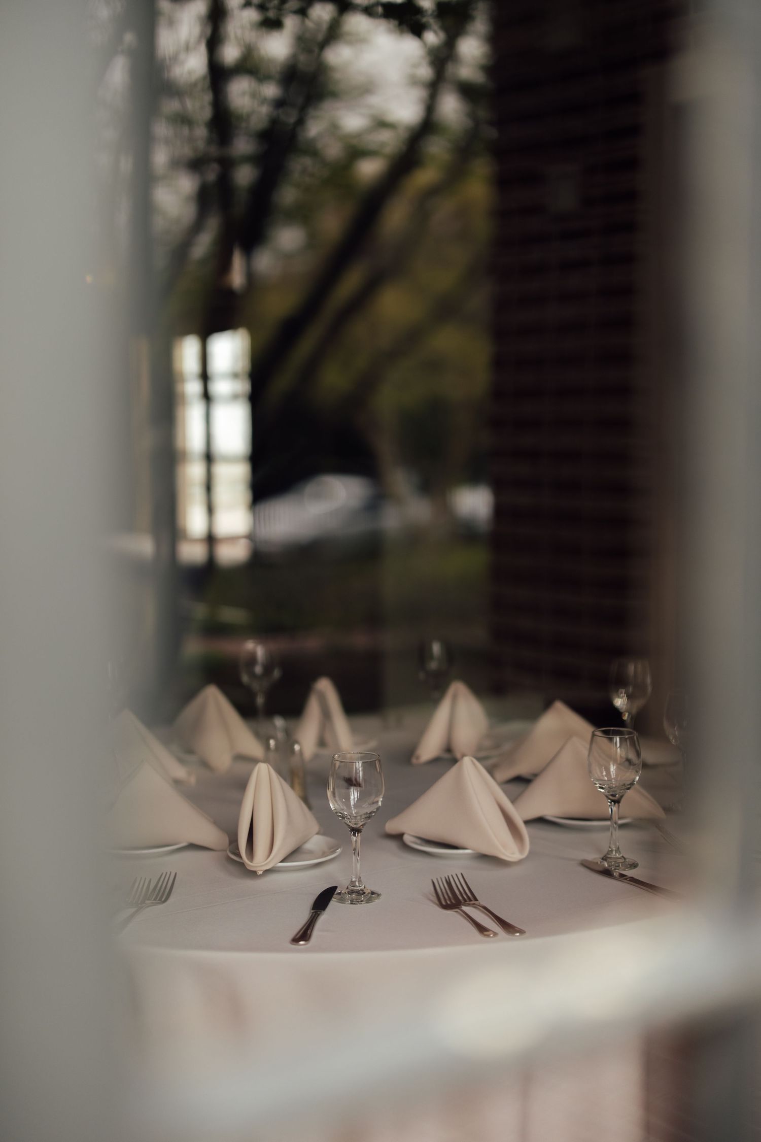 Elegant restaurant table set with folded linen napkins, wine glasses, and silverware on a white tablecloth.