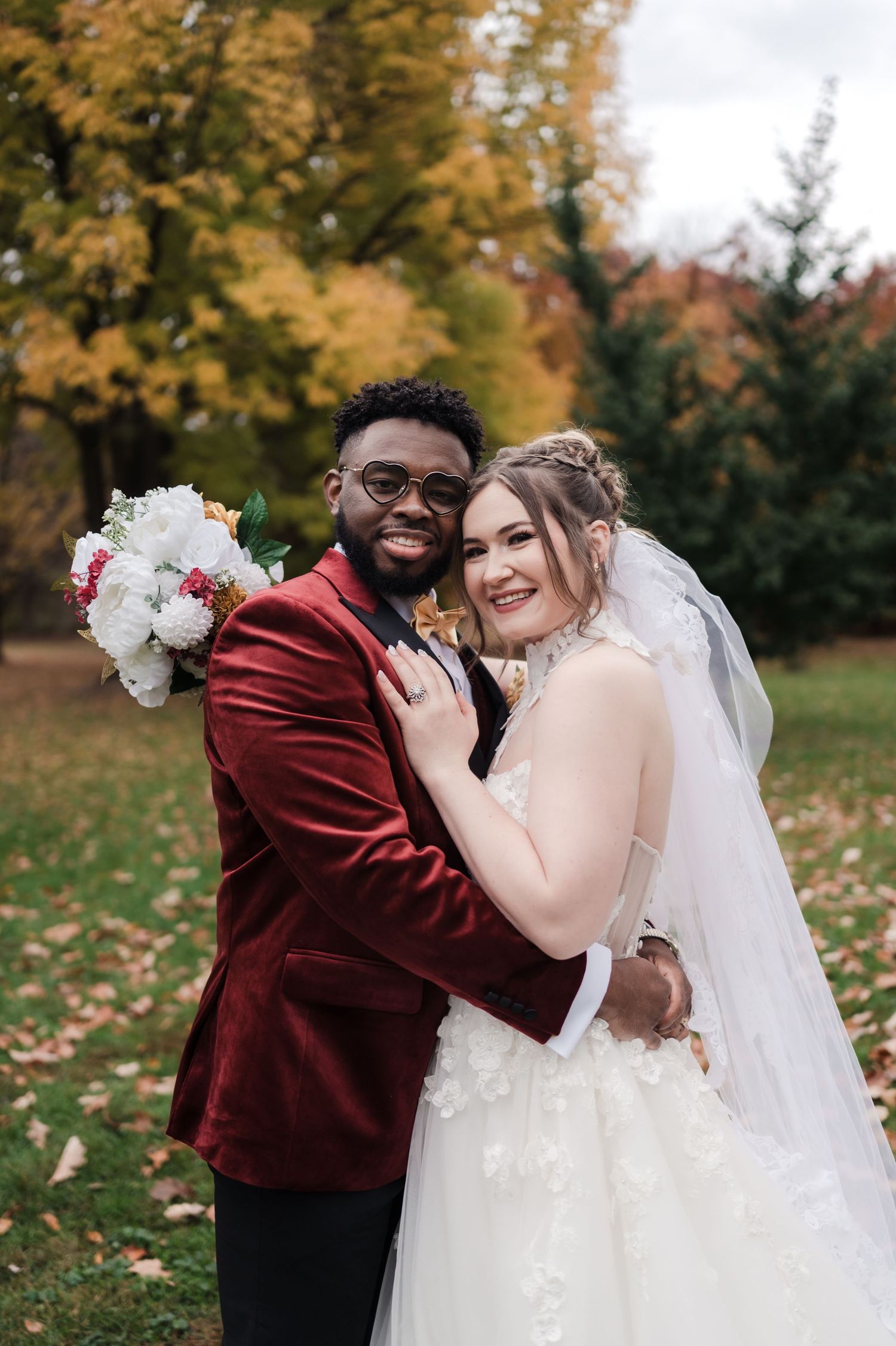 A couple shares joyful moments during their autumn wedding photoshoot with golden foliage in the background.