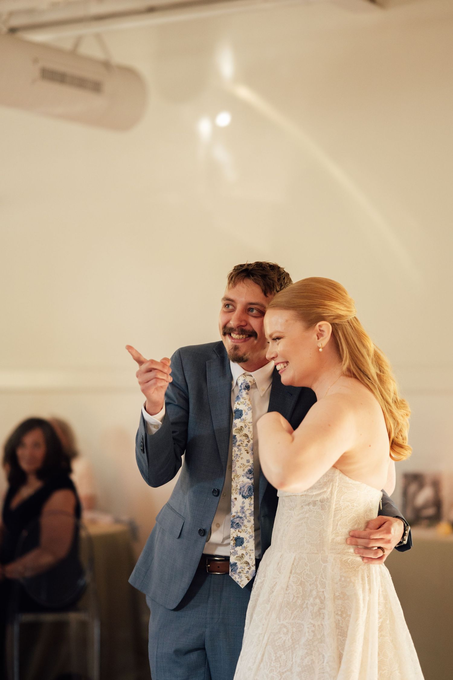 Bride and groom share a joyful first dance, laughing together at their wedding reception.