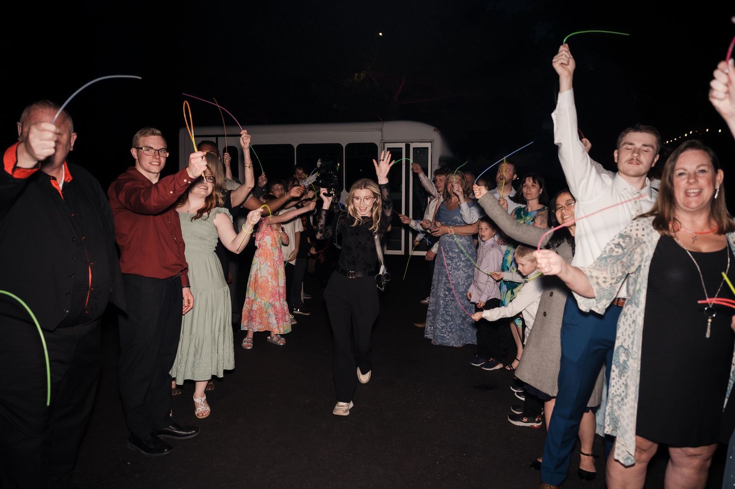 Wedding guests celebrating with light-up wands during festive nighttime grand exit sendoff ceremony.