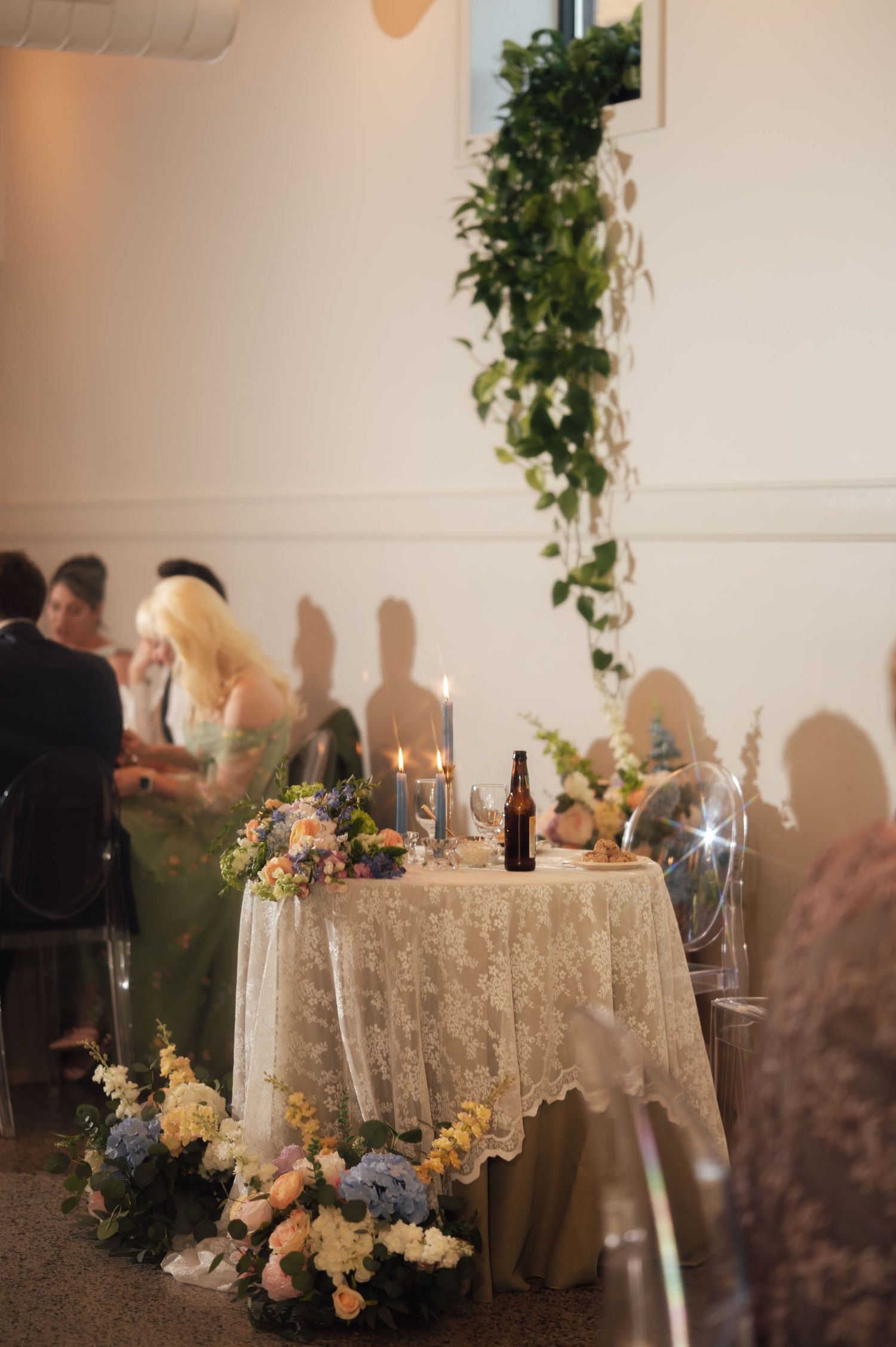 Elegant wedding sweetheart table with lace cloth, candles, and pastel floral arrangements at a romantic reception.