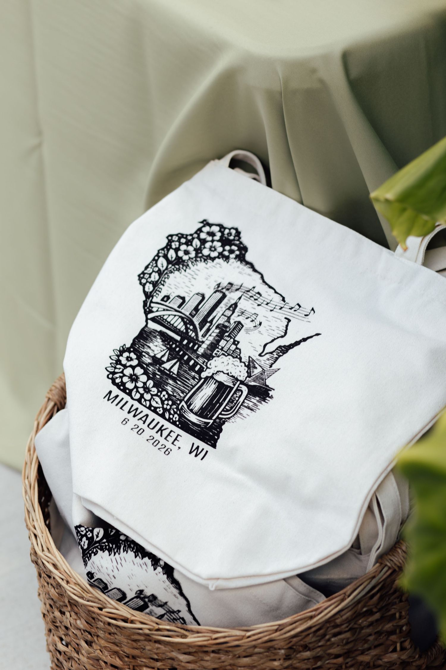 White tote bag in wicker basket with Milwaukee, WI skyline illustration and beer mug design dated 8.20.2020.