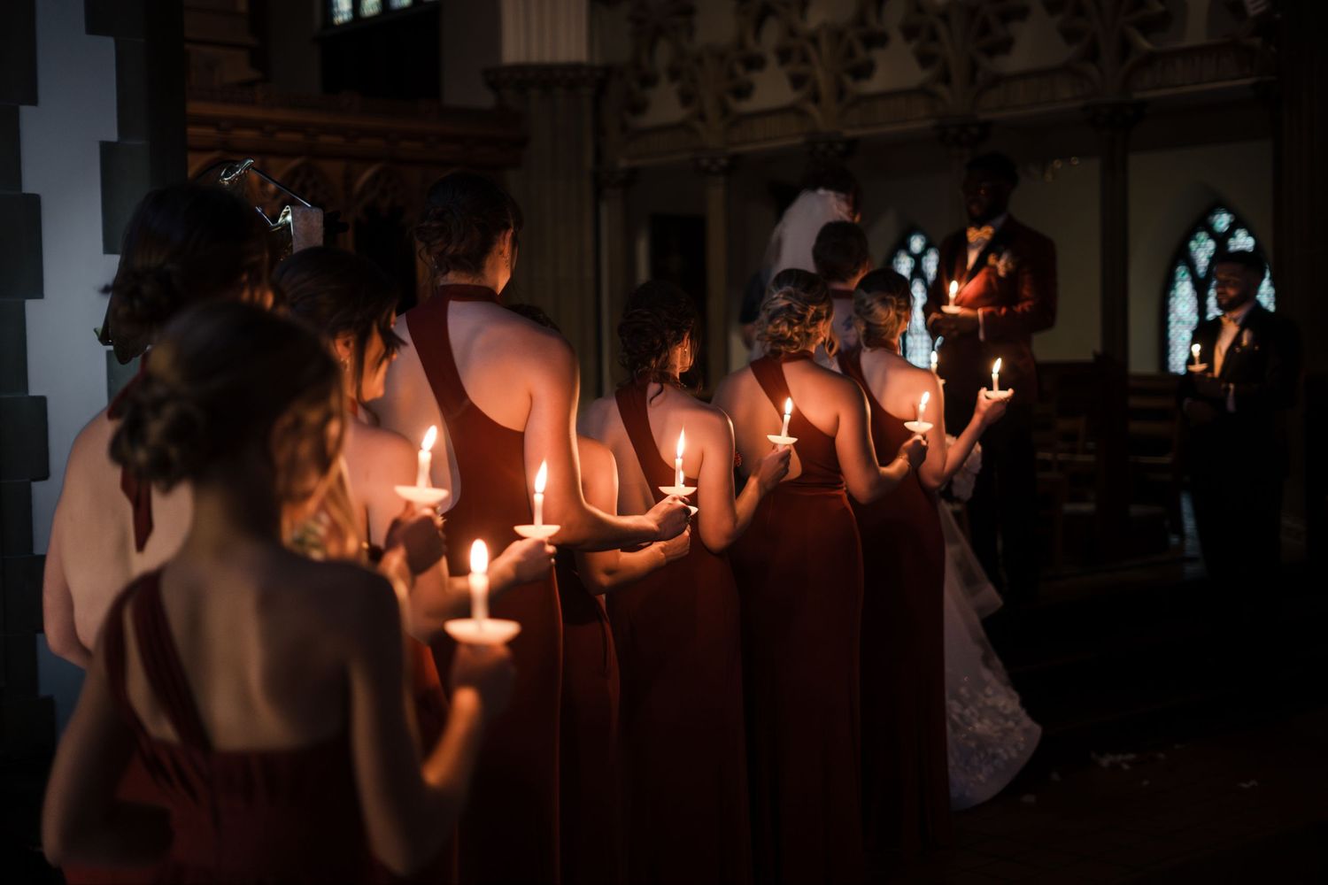 A group of people hold sparklers in a dimly lit room creating a festive atmosphere during a celebration.