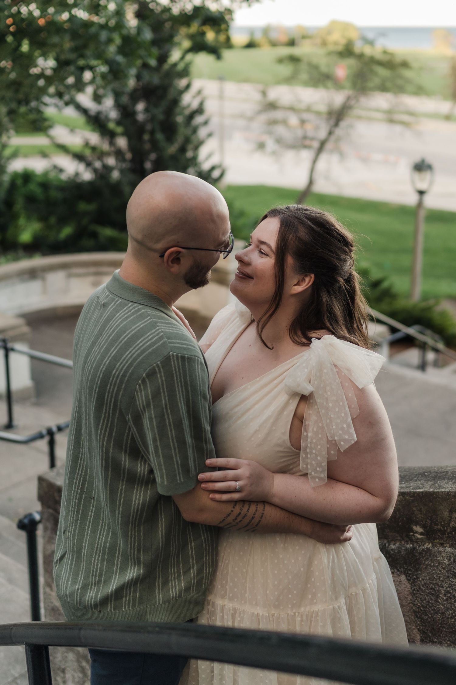 Smiling couple sharing a tender nose-to-nose moment on outdoor stone steps during golden hour engagement shoot.