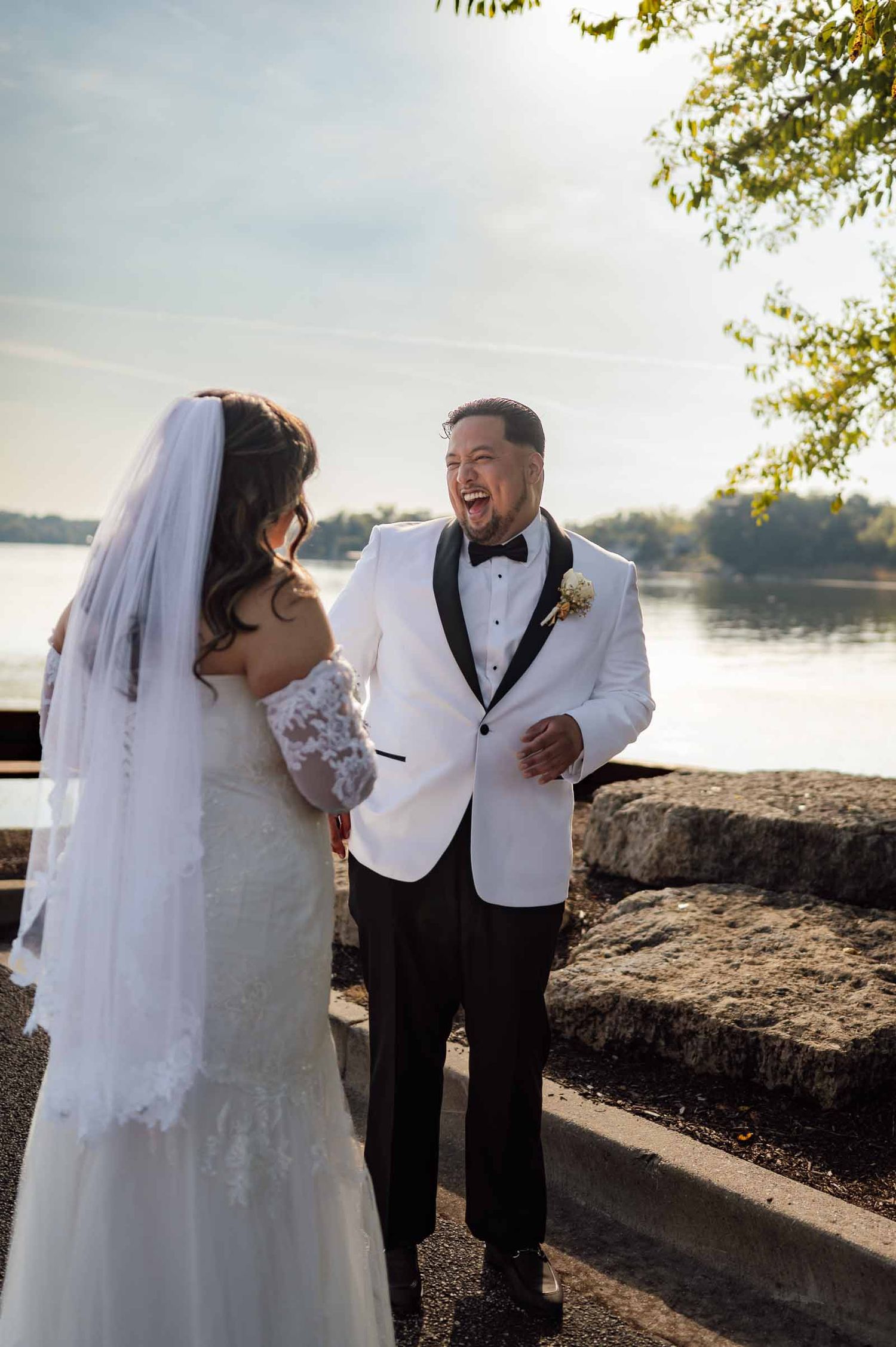 Groom reacts with joy and excitement during first look with his bride by a waterfront venue.