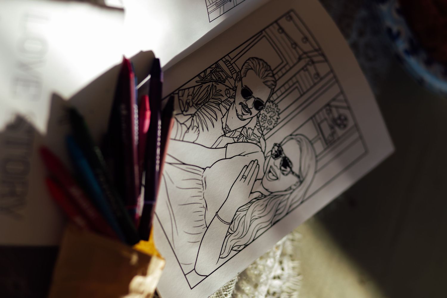 A coloring book page featuring cartoon characters beside colored markers on a table.