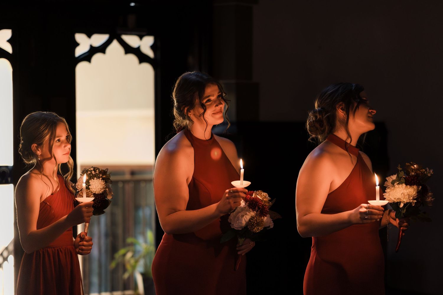 A series of candlelit portraits showing wedding party members holding glowing candles in a dimly lit setting.