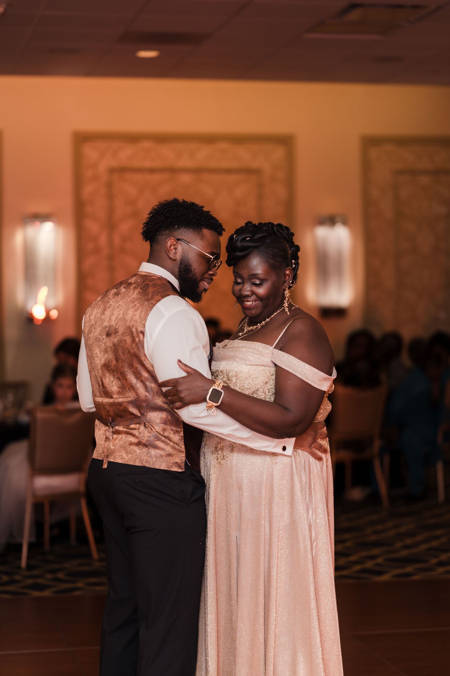 Wedding guests sharing an emotional embrace during a dance at an elegant ballroom reception.