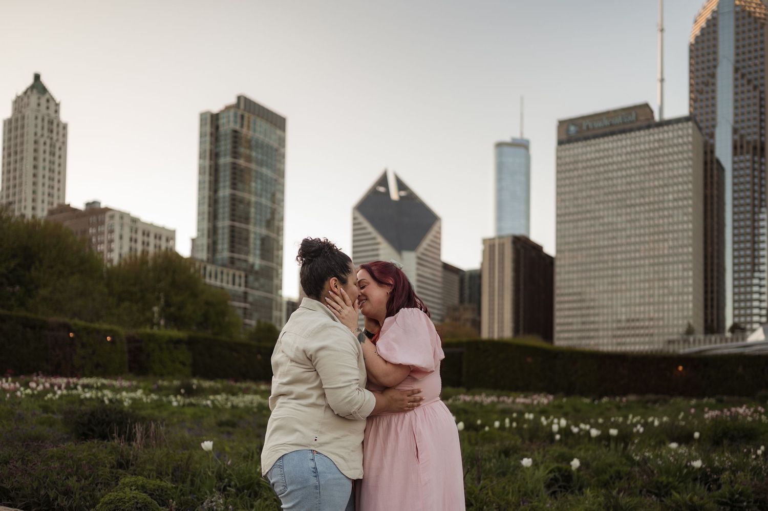Couple sharing a romantic kiss in Chicago's Millennium Park with city skyline in background.