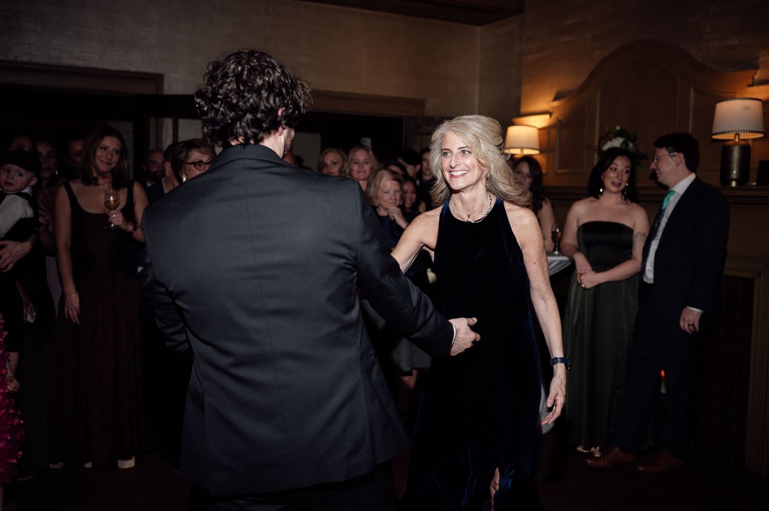 Elegant couple dancing at a formal black-tie event surrounded by guests in evening wear.