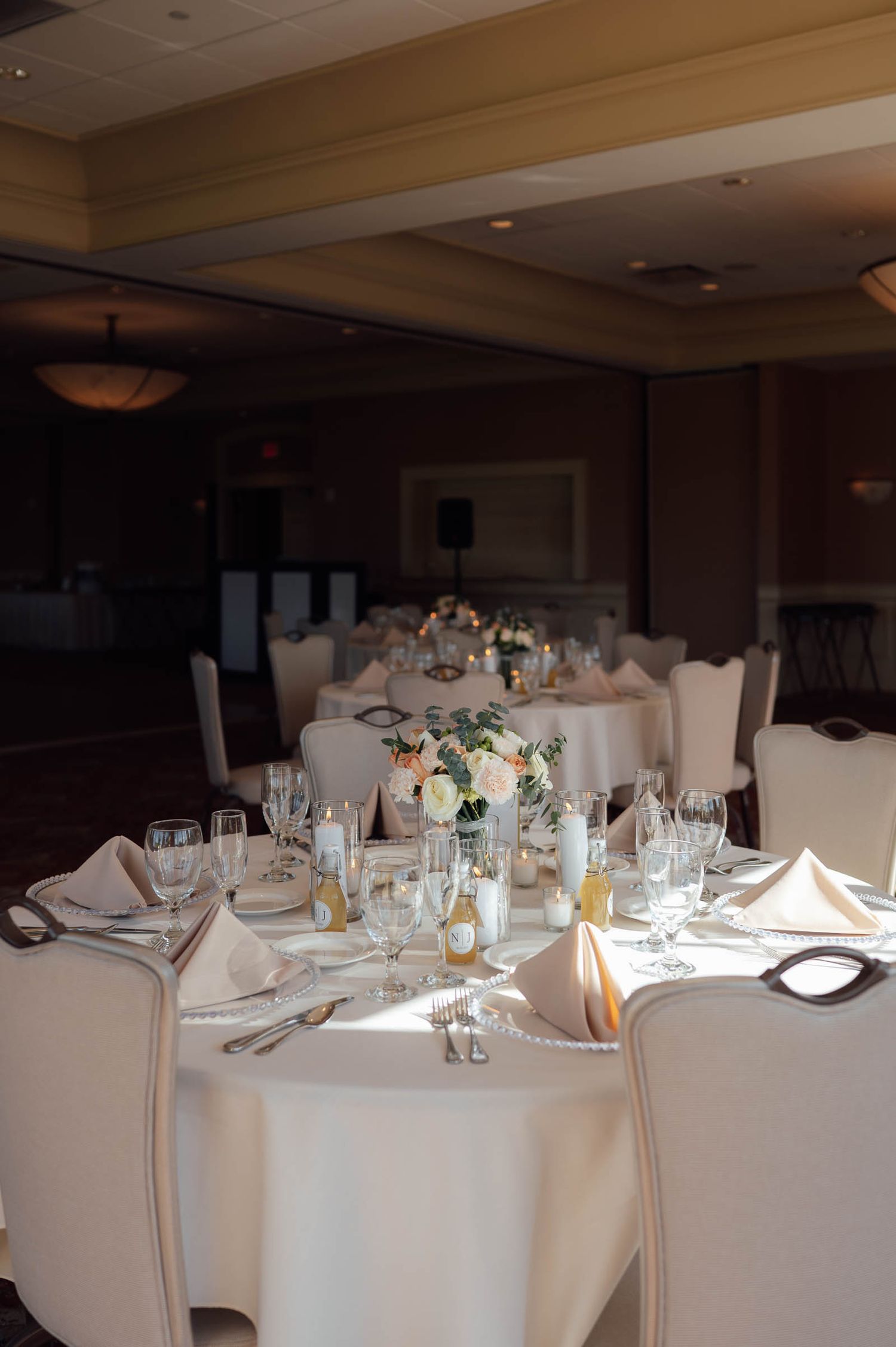 Elegant white wedding reception table with floral centerpiece, fine china, and crystal glassware.