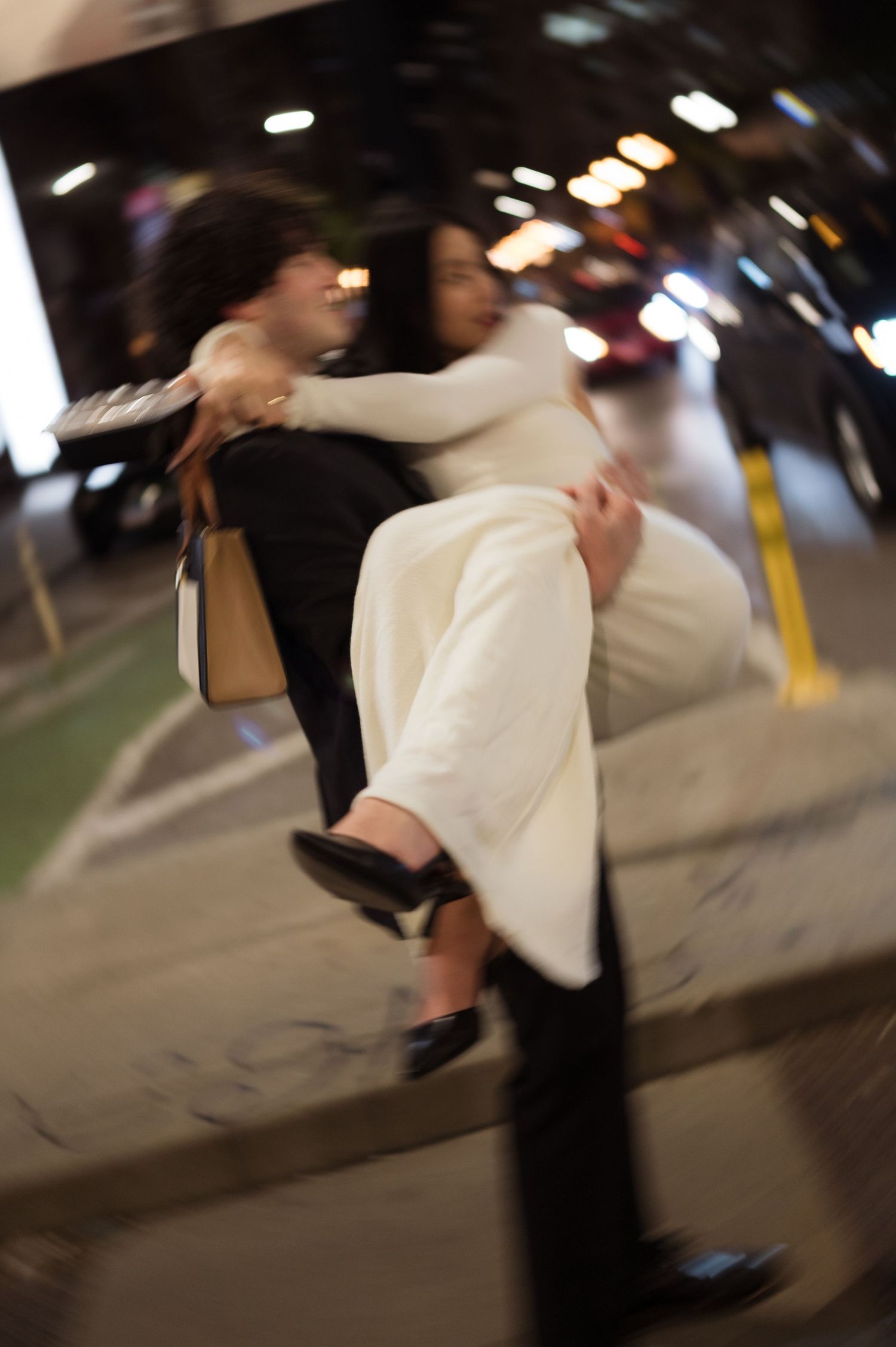 Motion blur photo of groom carrying bride on a Chicago sidewalk capturing a joyful wedding moment.