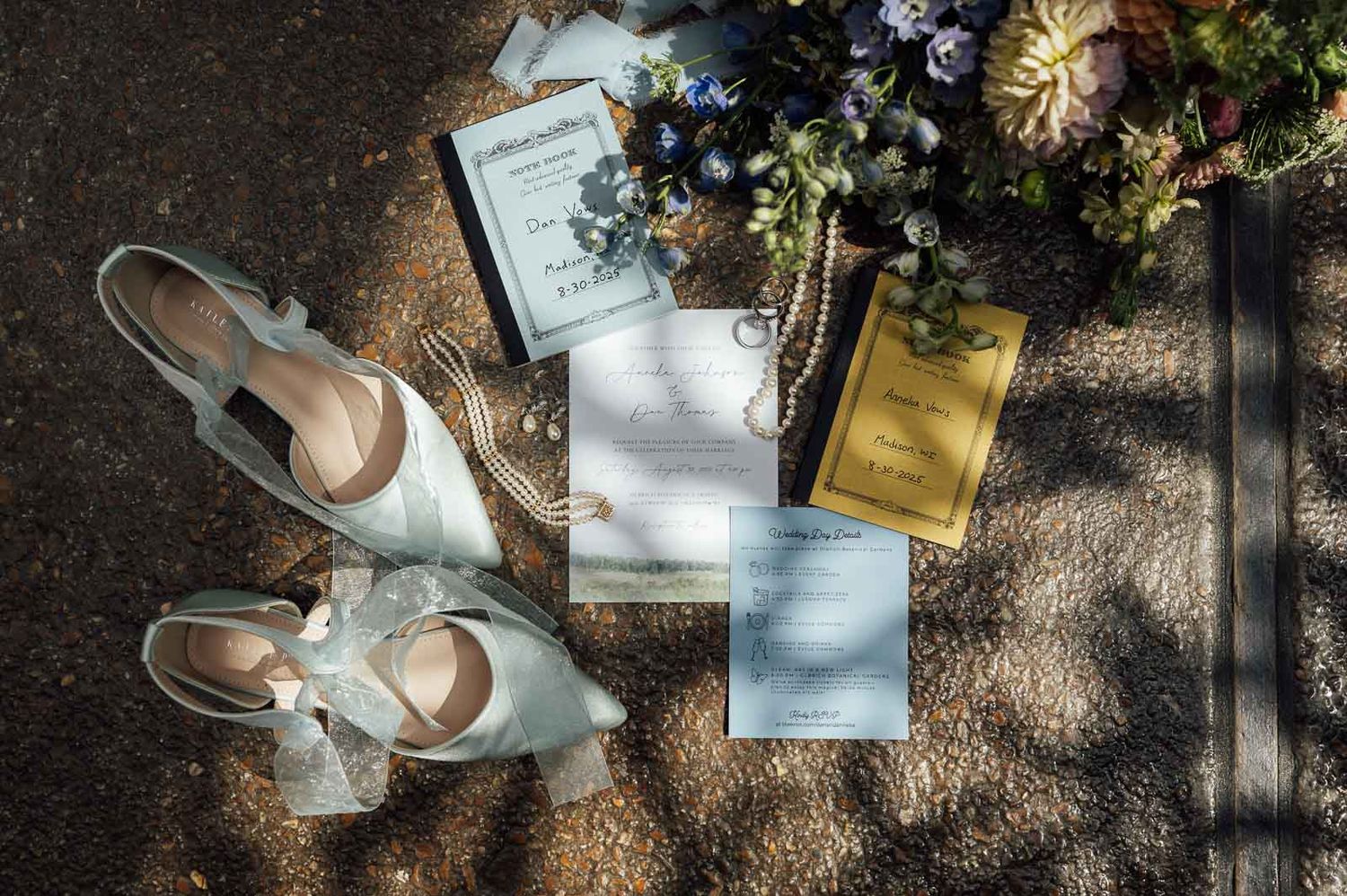 Wedding flat lay featuring bridal shoes, invitations, rings, and floral bouquet on ground.