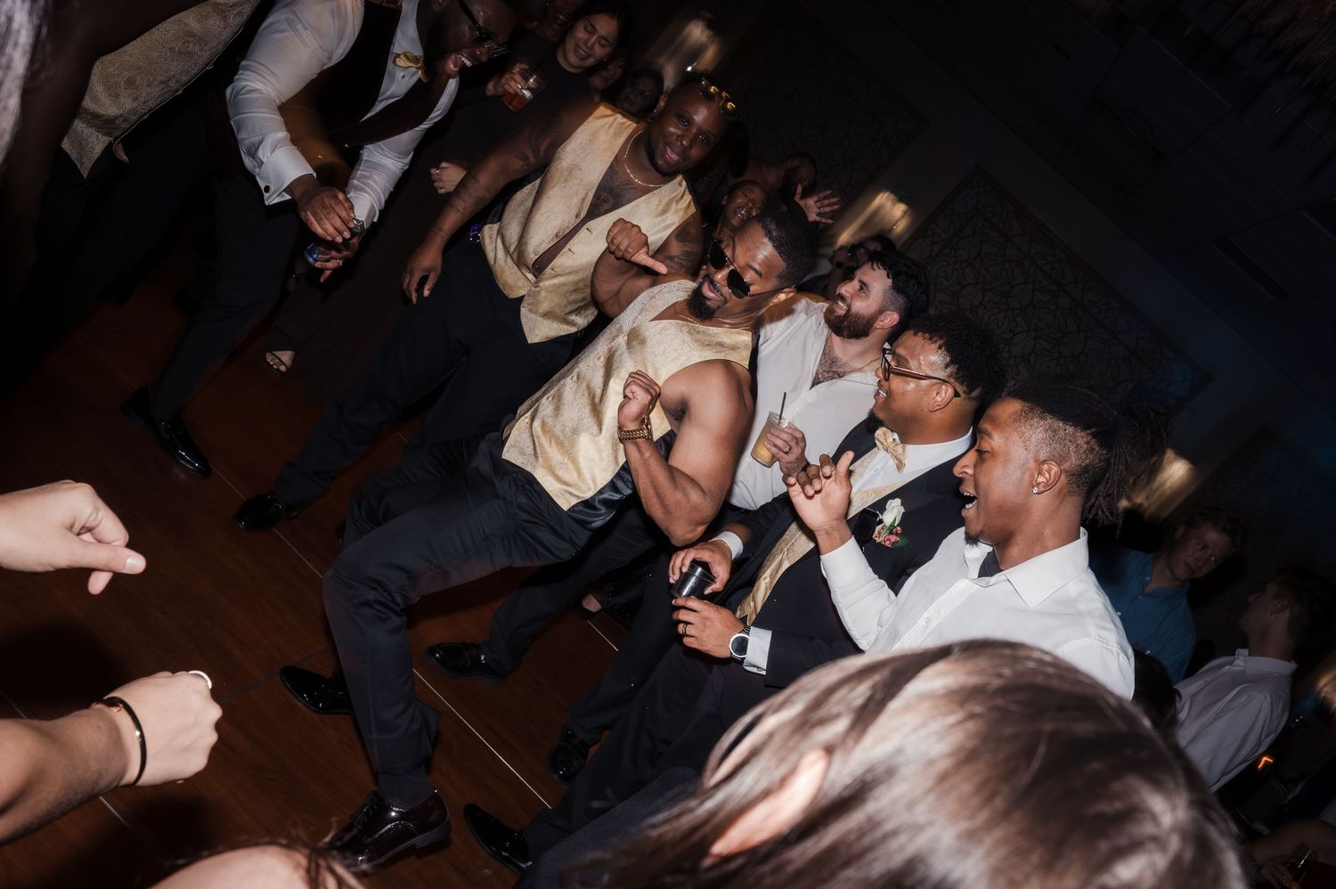 A crowd of people dancing and having fun at a nightclub or party with dark atmospheric lighting.