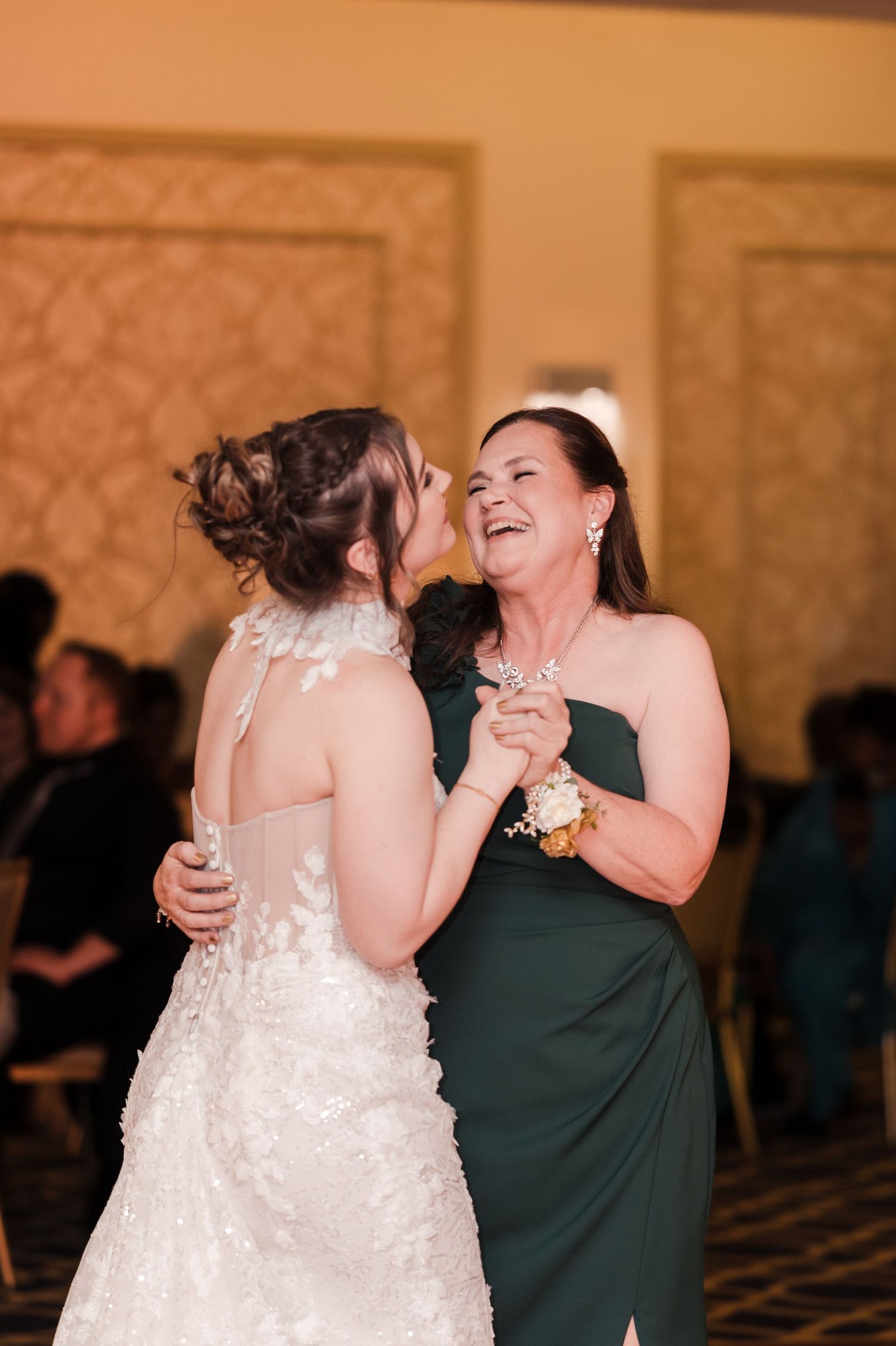 Two people share a joyful moment dancing together at a formal event in an elegant ballroom.